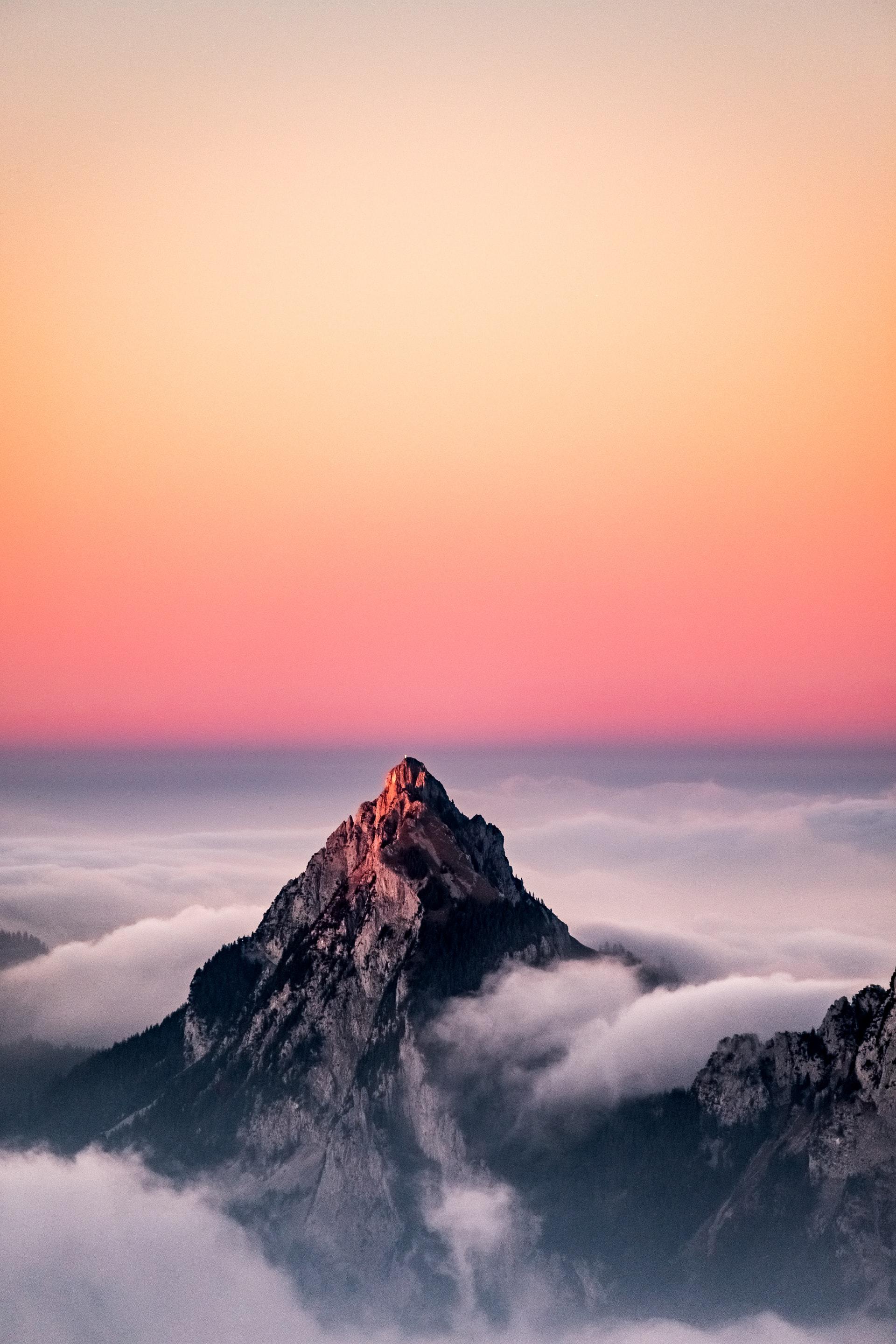 عکس زمینه قله کوه میان ابر در افق طلوع صبح پس زمینه